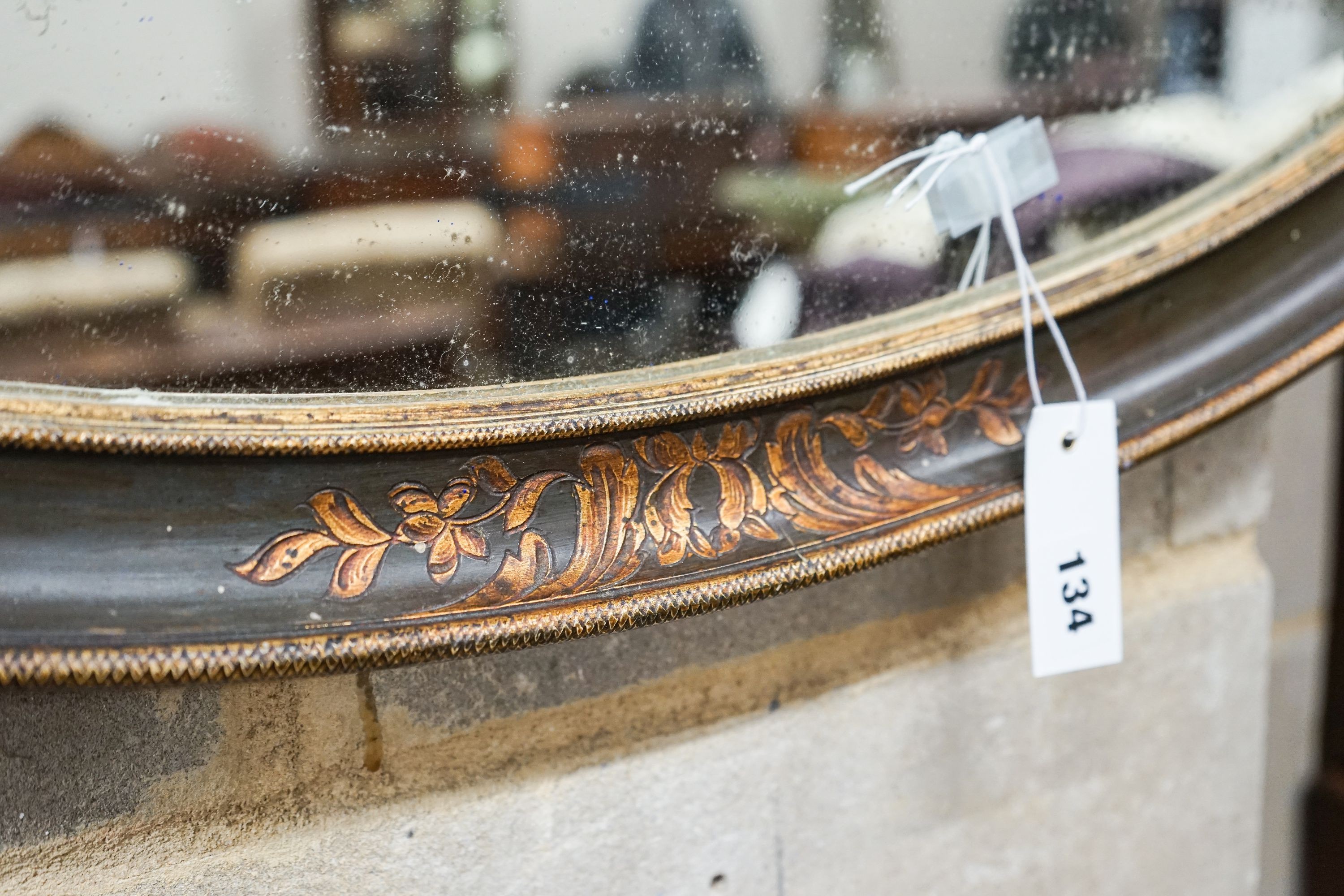 An oval painted parcel gilt bevelled wall mirror, width 84cm, height 51cm